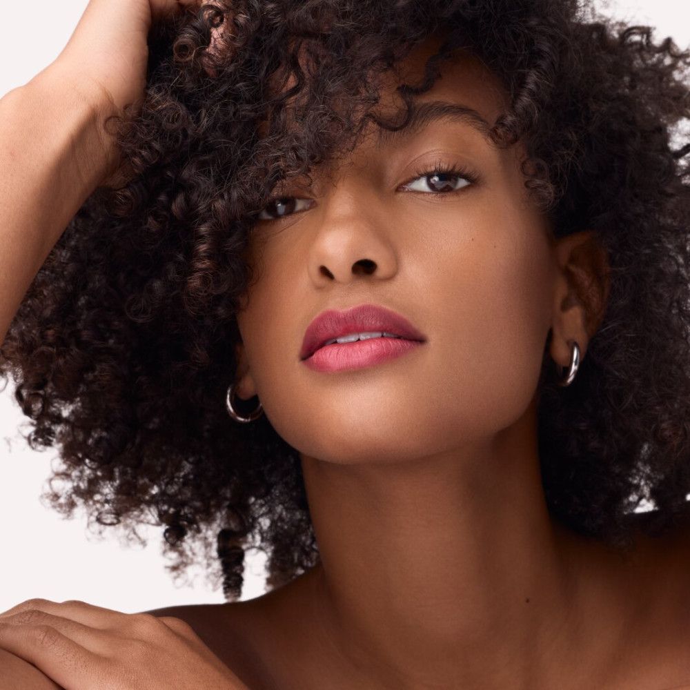 Porträt einer Frau mit Lippenstift. Dunkle Haare, silberne Ohrringe. Lippenstift in Rot.