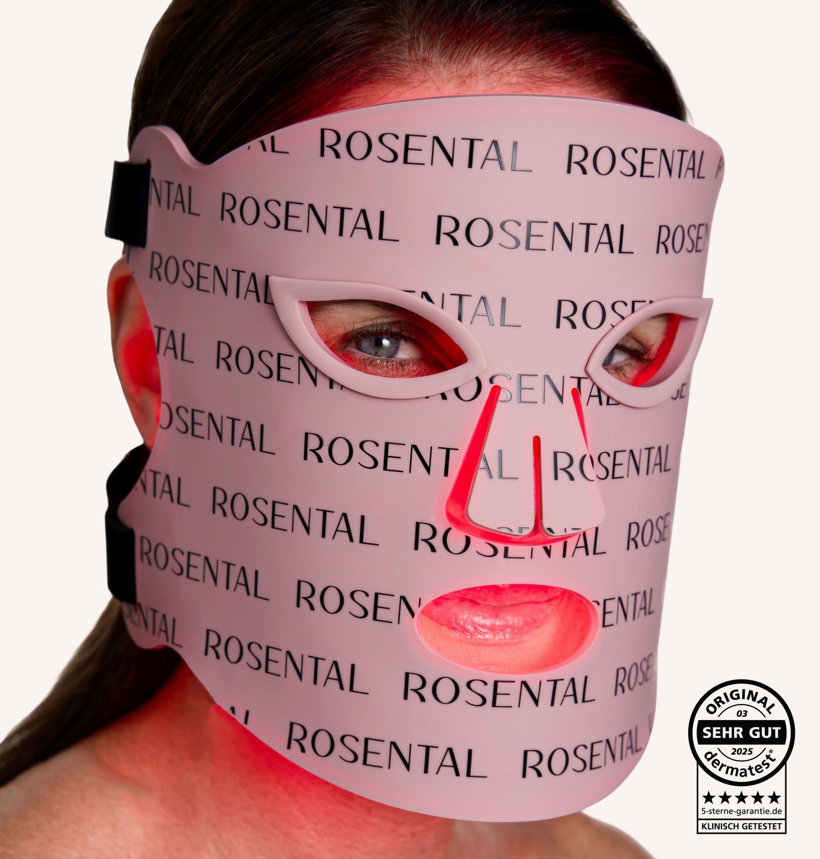 Person trägt eine rosa LED-Gesichtsmaske. Der Schriftzug ROSENTAL ist wiederholt aufgedruckt. Zertifizierungslogo.