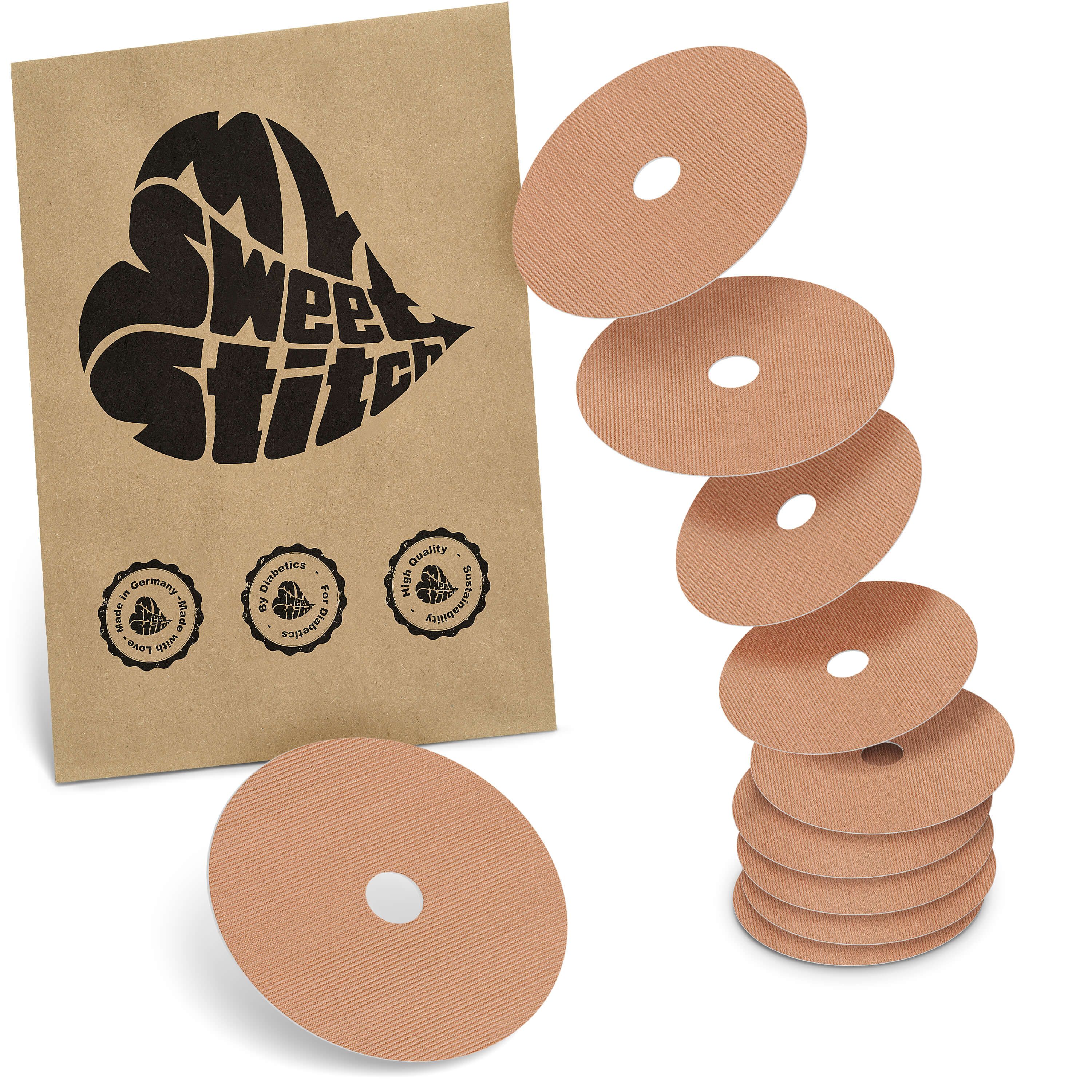 Beige runde Pflaster mit Loch, neben brauner Verpackung mit Logo. Einige Pflaster gestapelt.