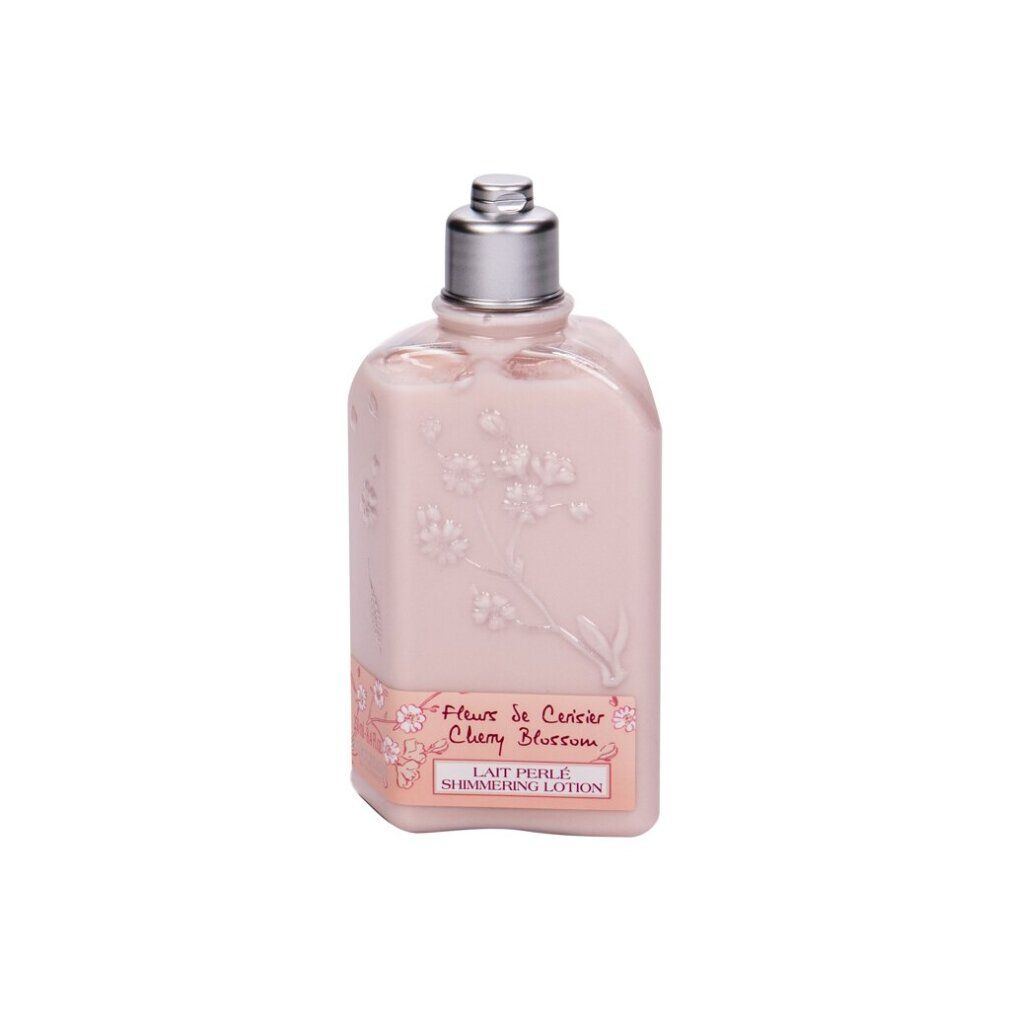 Rosa Flasche mit silbernem Deckel. Aufschrift: Fleur de Cerisier Cherry Blossom Lait Perlé Shimmering Lotion. Blumenmuster.