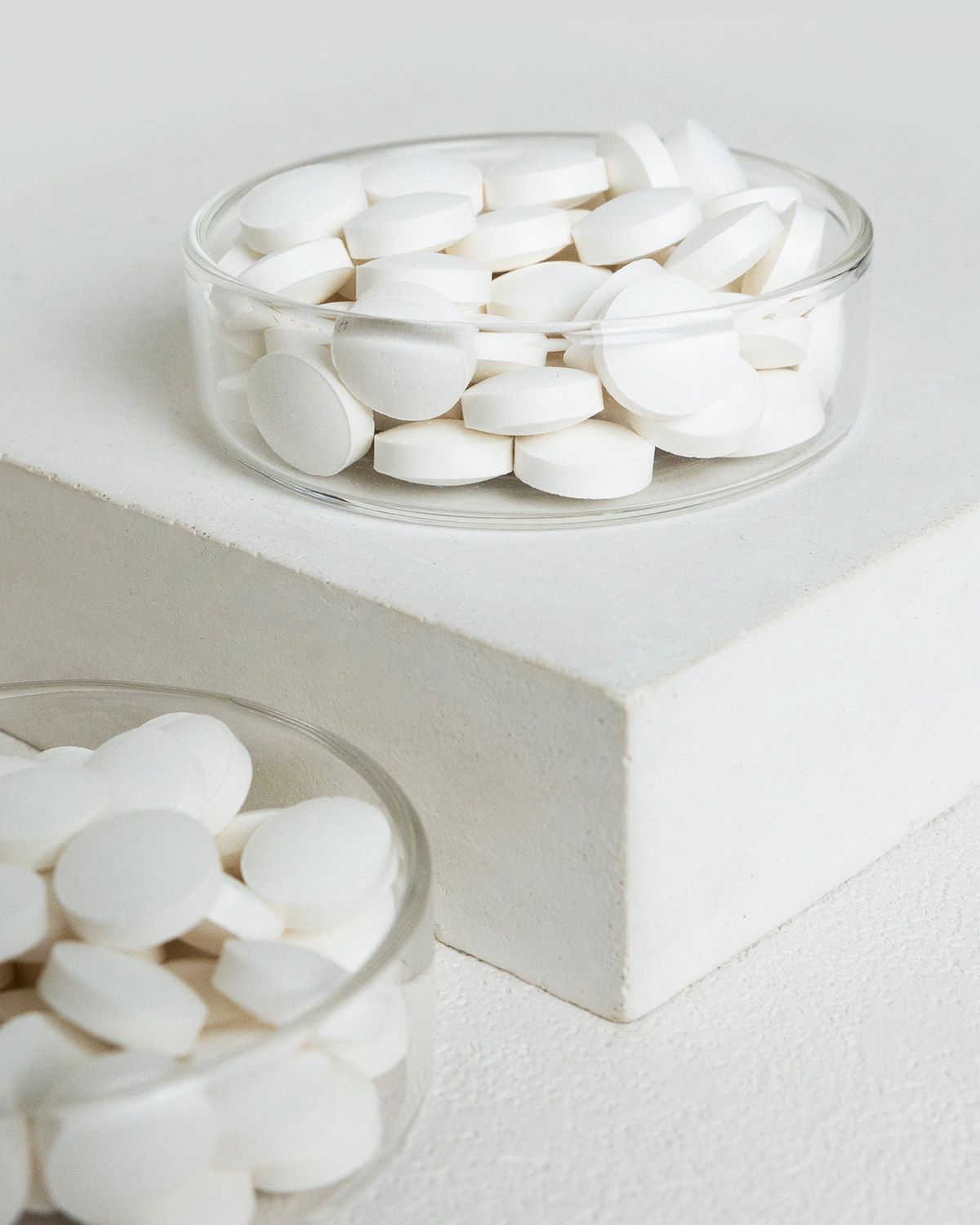 Zinkbisglycinat Tabletten in zwei Gläsern auf weißem Untergrund.