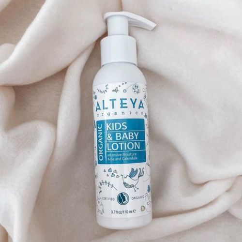Weiße Flasche mit Pumpe. Aufschrift: Alteya Organics, Kids & Baby Lotion. Auf weißem Stoff platziert.