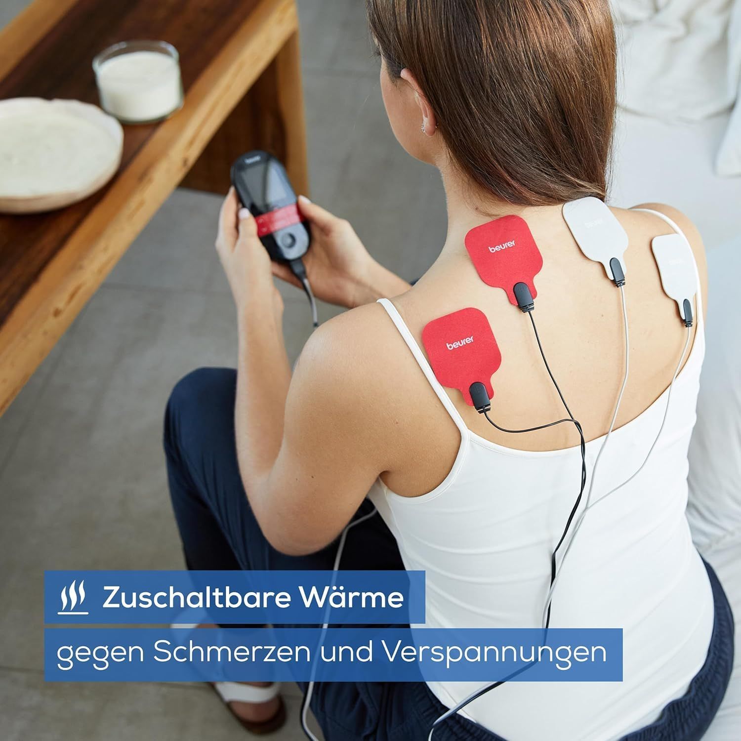 Person mit Elektroden am Rücken. Gerät in der Hand. Text: Zuschaltbare Wärme gegen Schmerzen und Verspannungen.