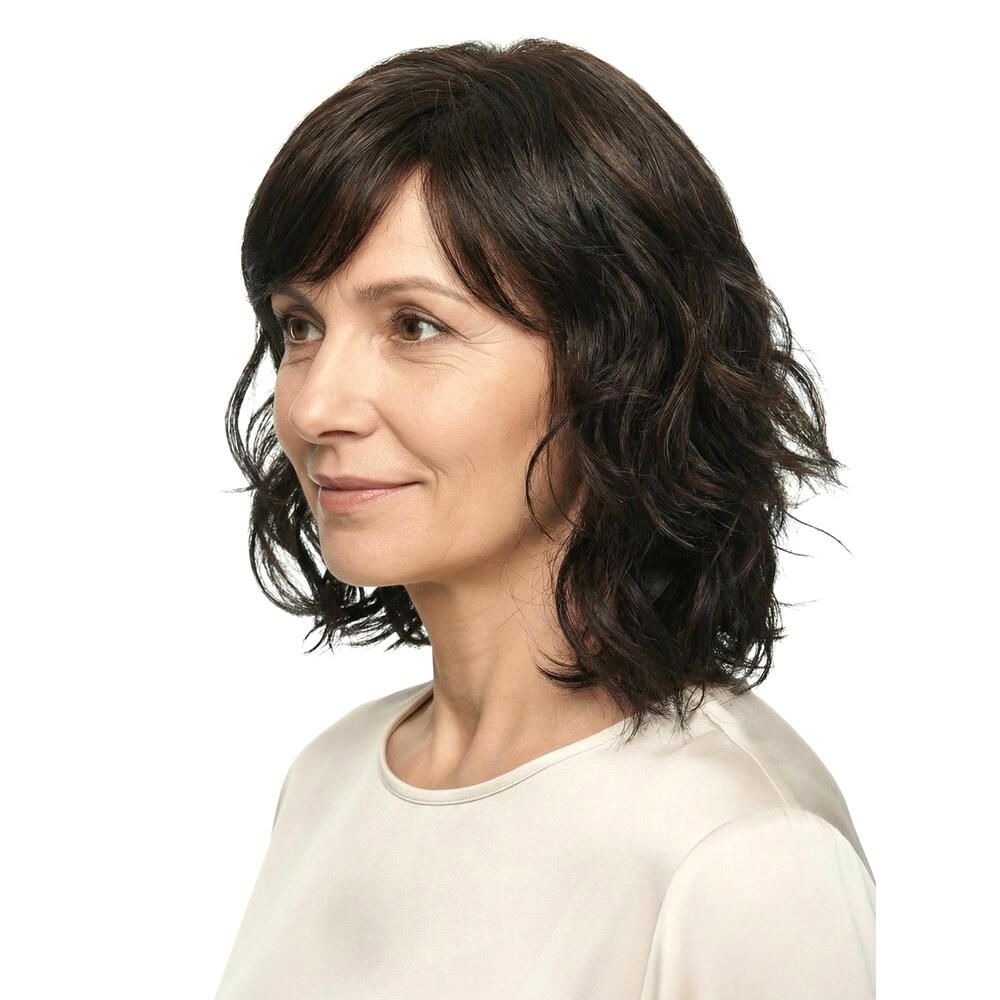 Perücke Capri, braun, gewellt. Frau im Profil, Blick nach rechts. Helles Oberteil.