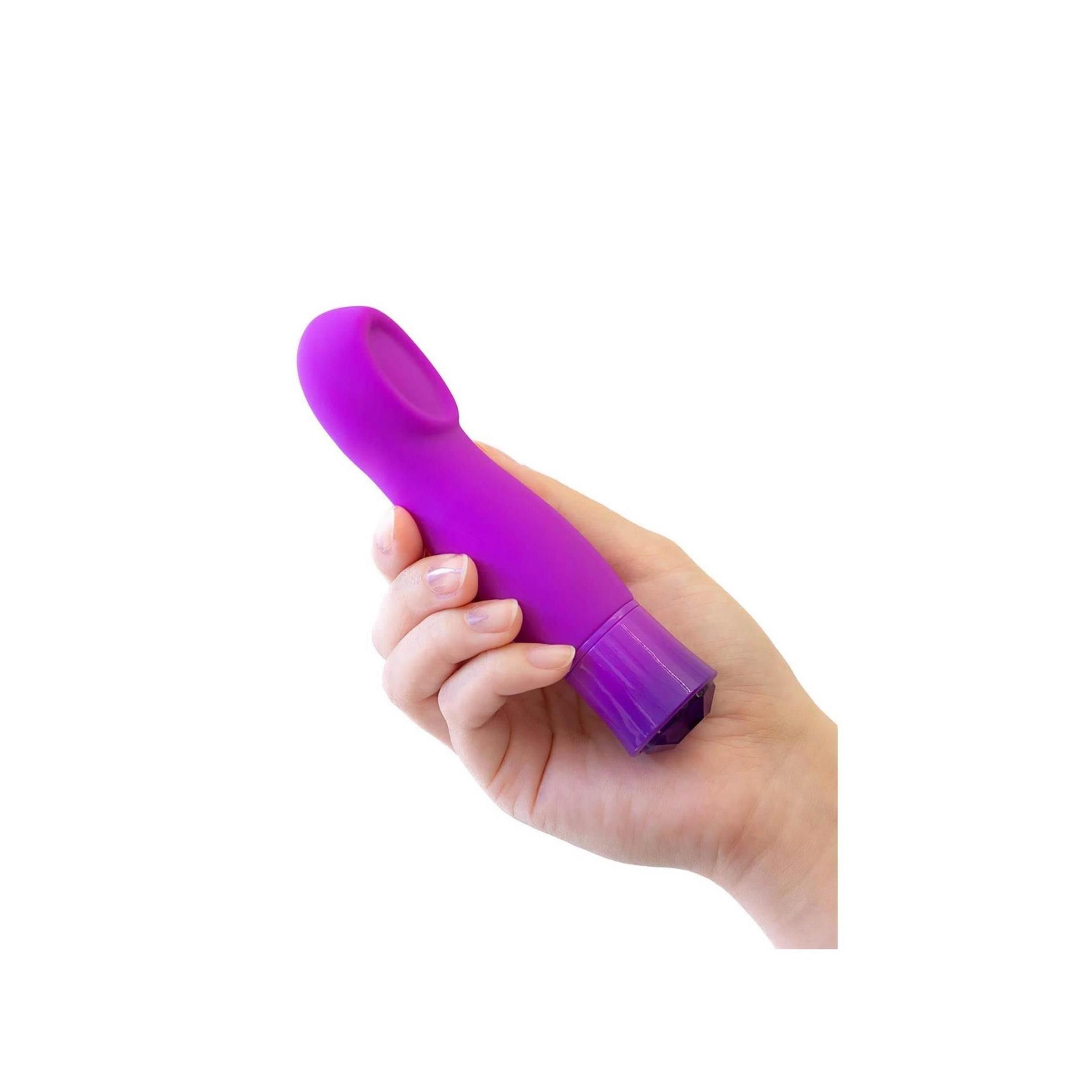 Eine Hand hält einen lila Vibrator. Der Vibrator hat eine ovale Spitze und eine Kristallspitze.