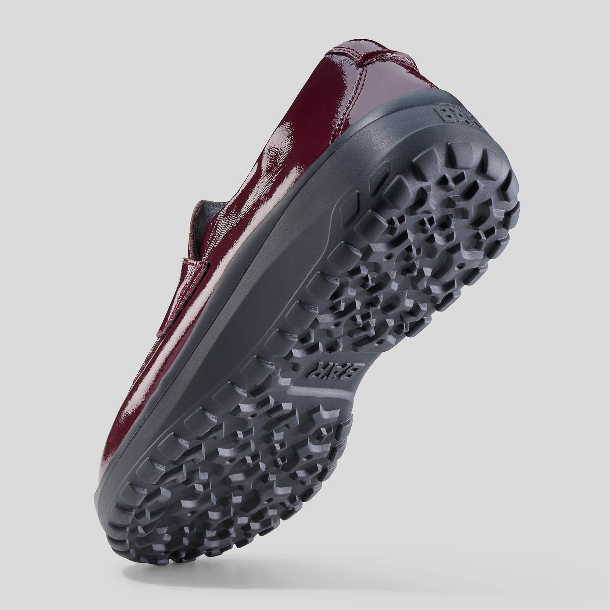 Unterseite eines bordeauxfarbenen Damen-Slippers mit breiter Passform. Schwarze Sohle mit Profil.