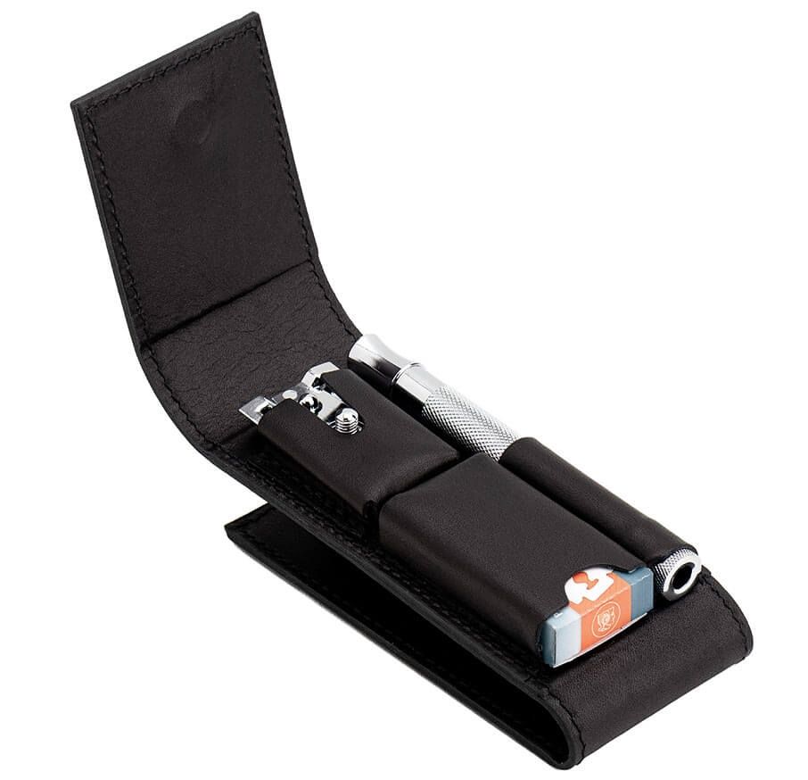 Schwarzes Lederetui mit Rasierhobel, Rasierklingen und Zubehör. Geöffnet, Inhalt sichtbar.