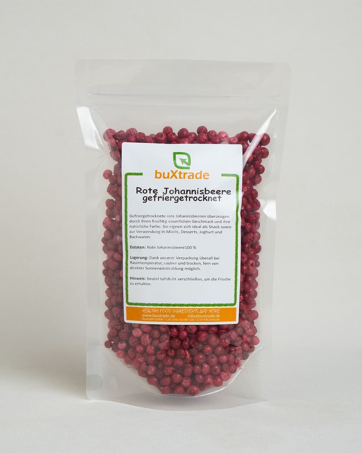 Gefriergetrocknete rote Johannisbeeren in einem Klarsichtbeutel mit Etikett. Kleine Schale mit Beeren daneben.