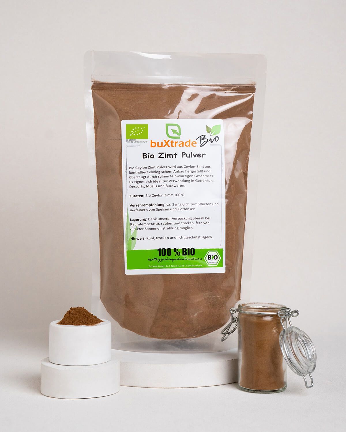 Bio Zimt Pulver in einem Beutel, daneben eine kleine Schale mit Pulver und ein Glas mit Zimt. Enthält Bio-Siegel.