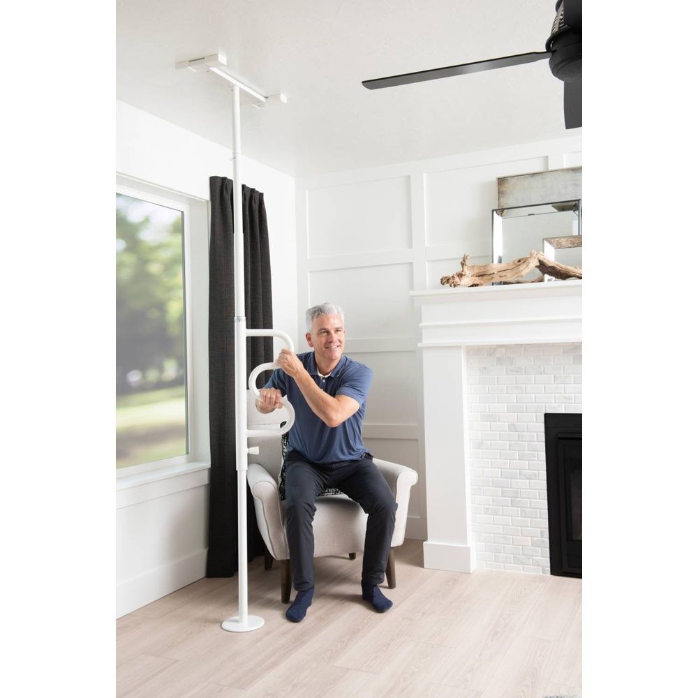 Ein Mann sitzt in einem Stuhl und hält sich an der weißen Boden-Deckenstange mit Griff fest.