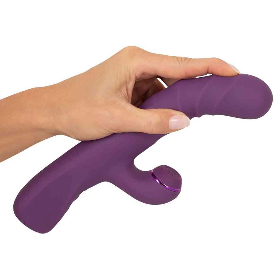 Hand hält lila Vibrator. Das Gerät hat eine geriffelte Oberfläche und einen gebogenen Arm.