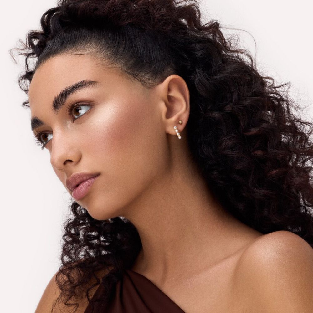 Porträt einer Frau mit Highlighter auf der Haut. Sichtbar sind Augen, Wangen und Haare.