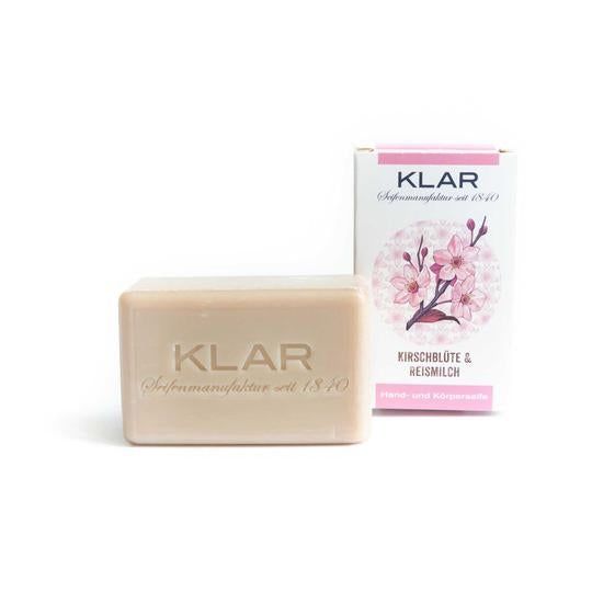 Seife mit Prägung "KLAR". Daneben Verpackung mit Kirschblüten-Motiv und Schriftzug "Kirschblüte & Reismilch".