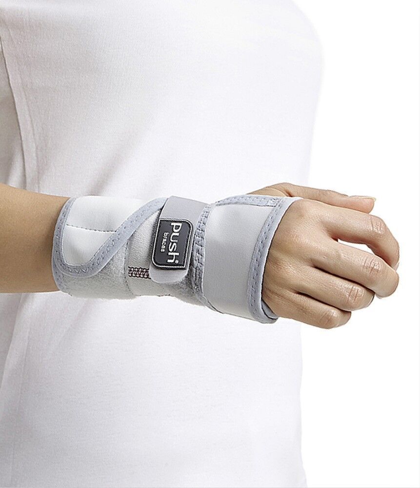 Handgelenkbandage, weiß mit grauem Rand und Klettverschluss. Marke Push. Am Handgelenk einer Person getragen.