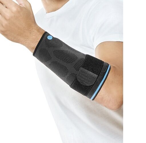 Person trägt eine graue und schwarze Armbandage. Klettverschluss und blauer Akzent sind sichtbar. Trägt ein weißes T-Shirt.