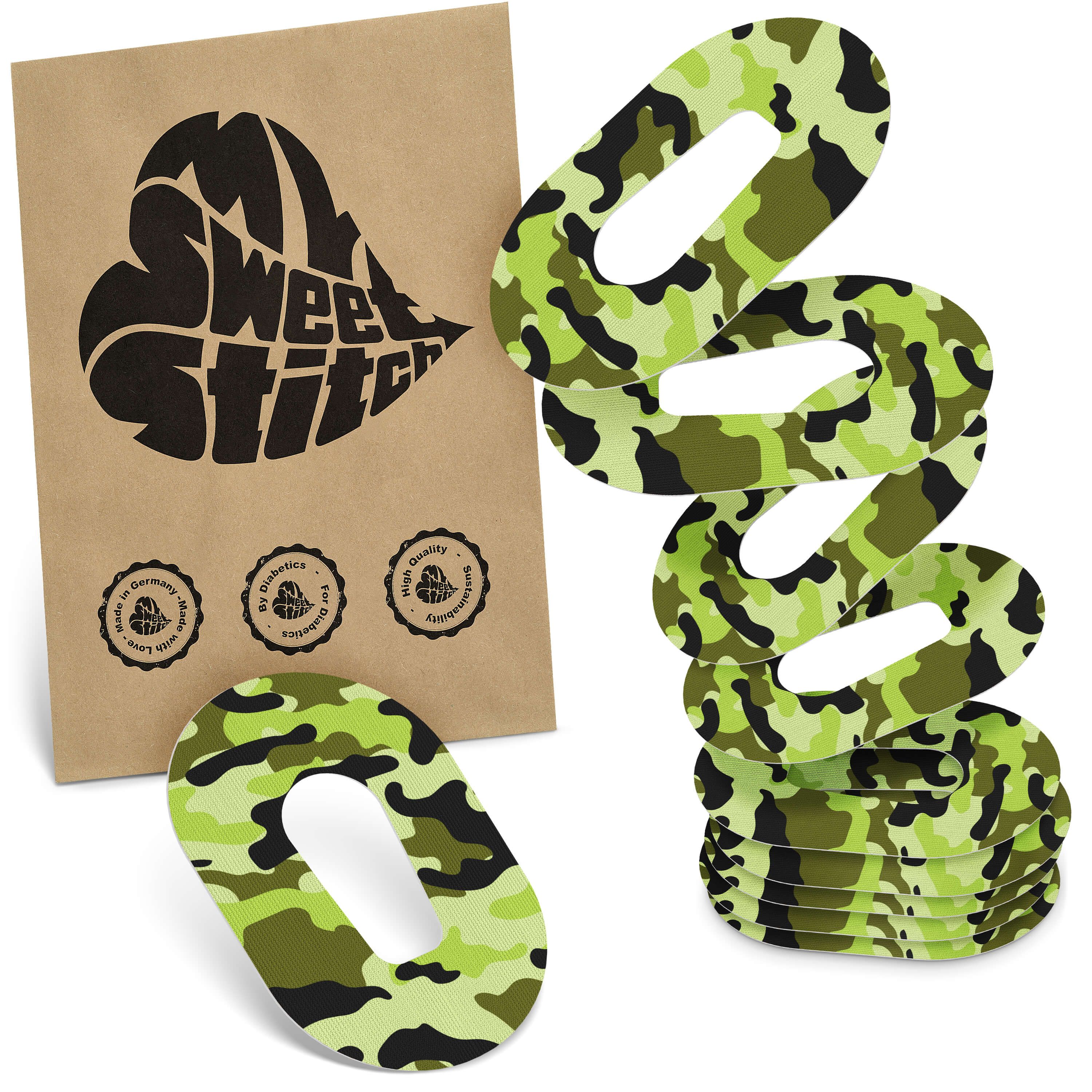 Oval geformte Pflaster in Tarnmuster. Braune Verpackung mit Logo und Qualitätssiegeln. Mehrere Pflaster gestapelt.