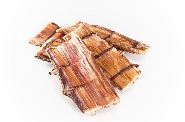 Getrocknetes Rinder-Schlundfleisch, braun und beige, in Stücken. Auf weißem Hintergrund.