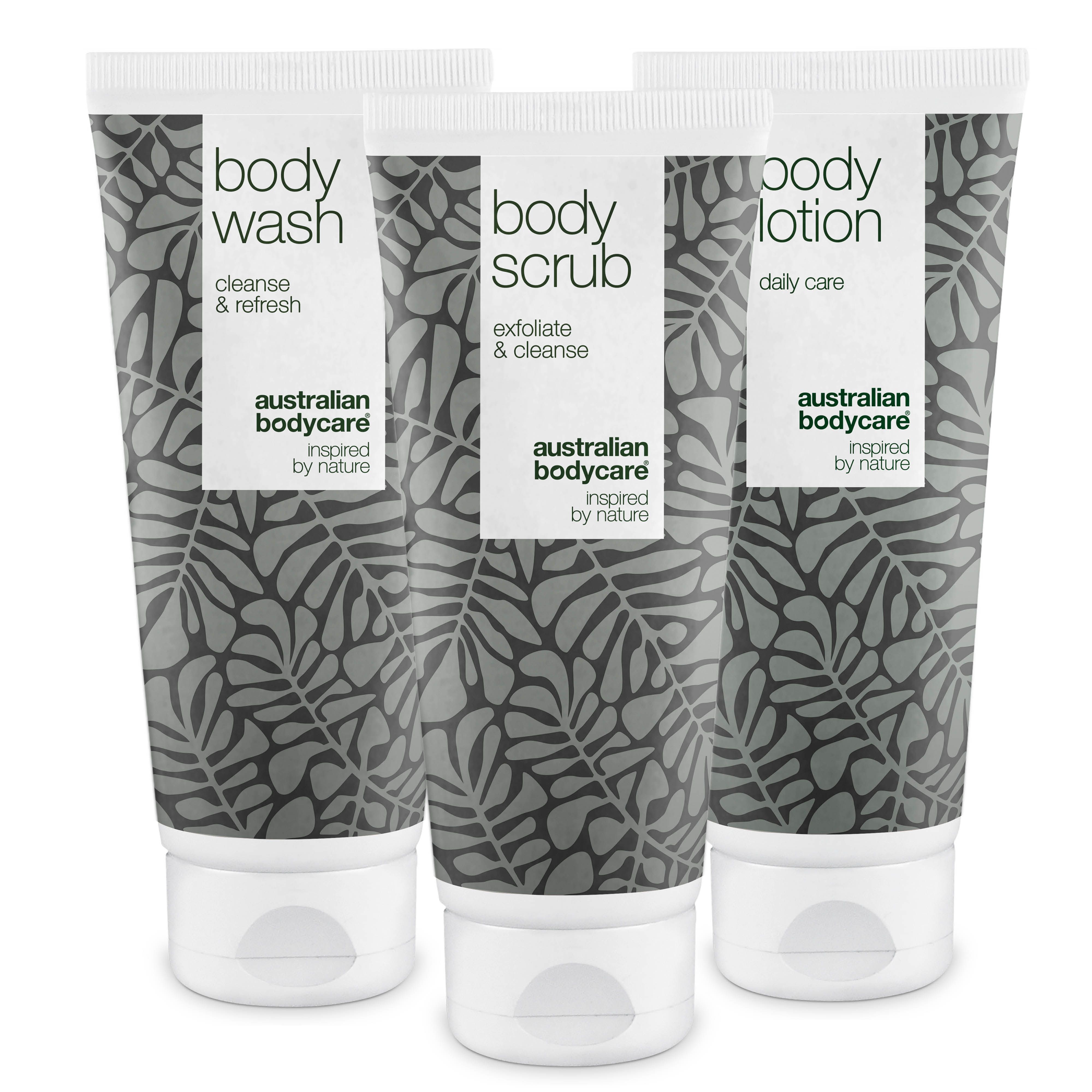 Drie tubes: Body Wash, Body Scrub, Body Lotion. Wit en grijs design met bladeren. Merknaam en productnamen.