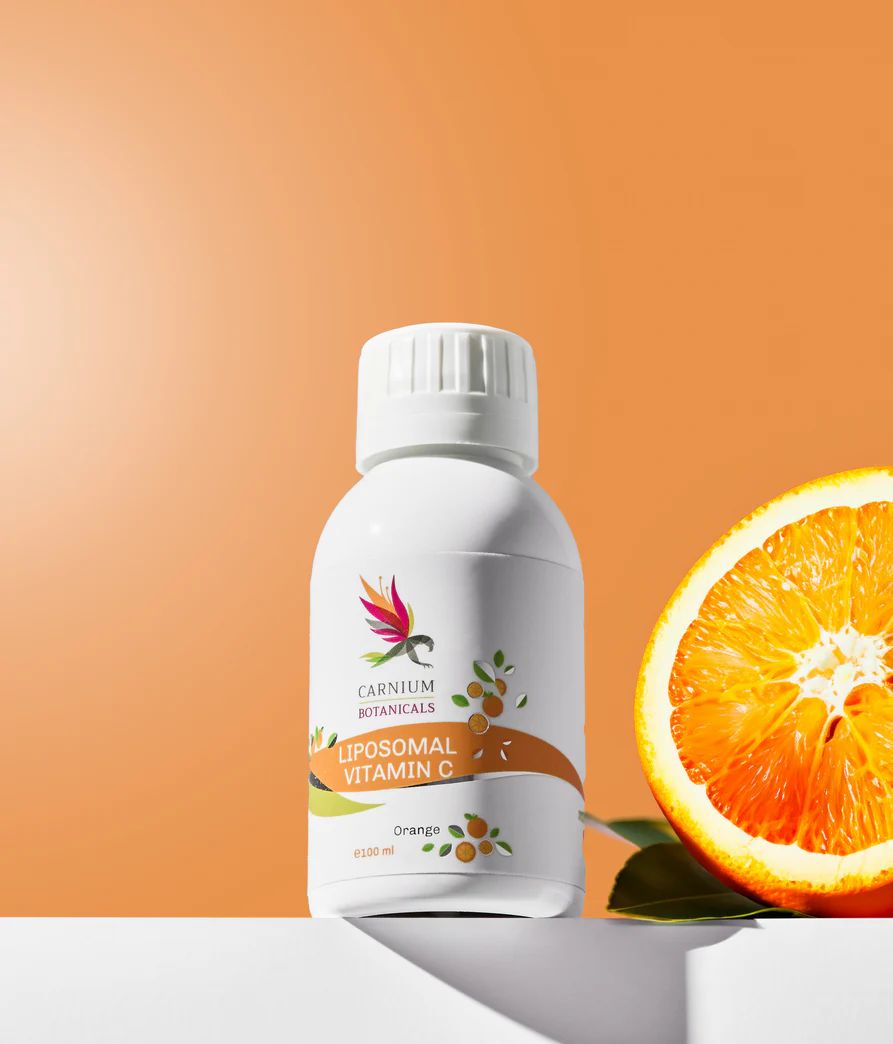 Weiße Flasche mit gelbem Etikett. Aufschrift: Carnium Botanicals Liposomales Vitamin C. Orange daneben.