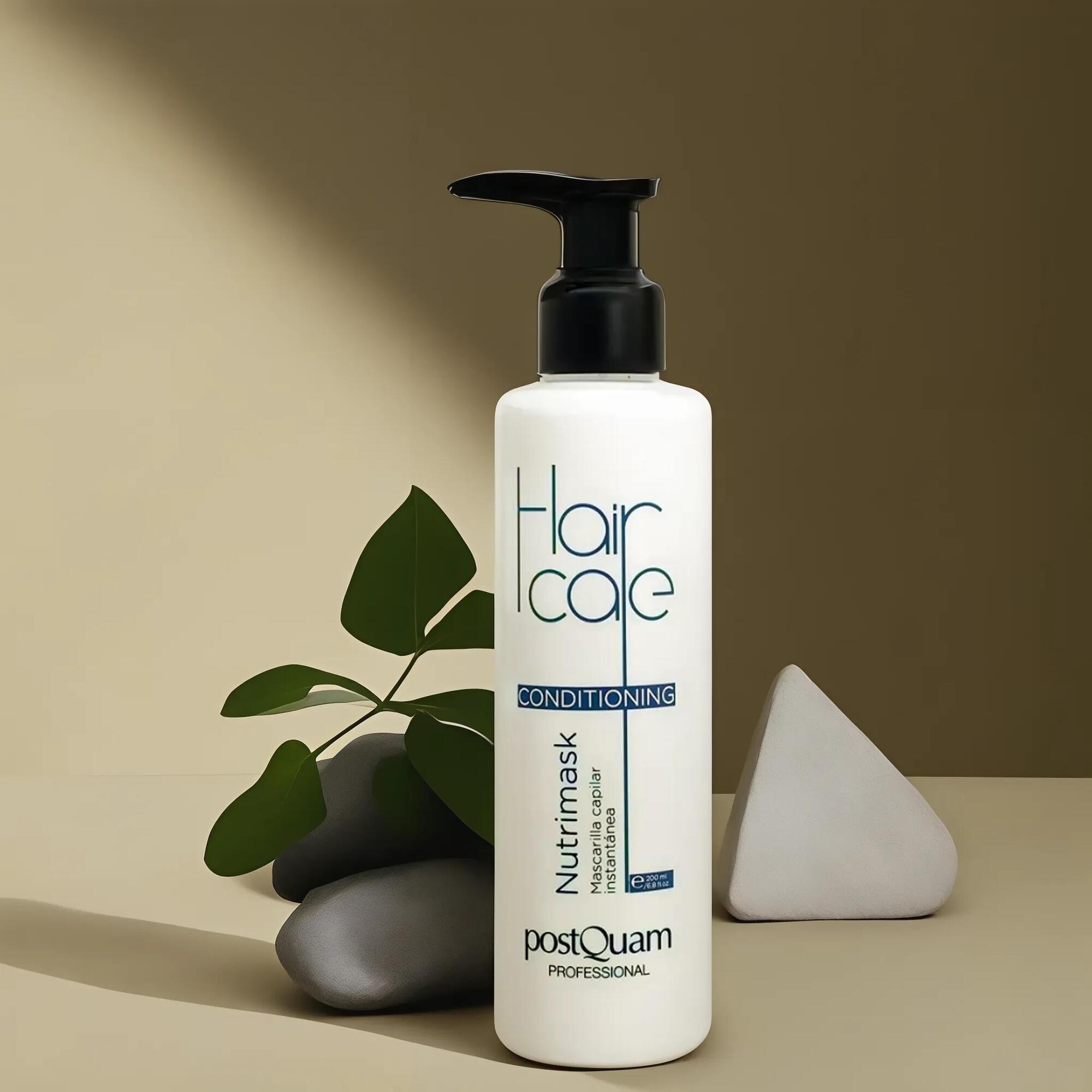 Weiße Flasche mit schwarzem Pumpkopf. 'Hair Care Conditioning' und 'Nutrimask' von Postquam. Dekoration mit Blättern und Stein.