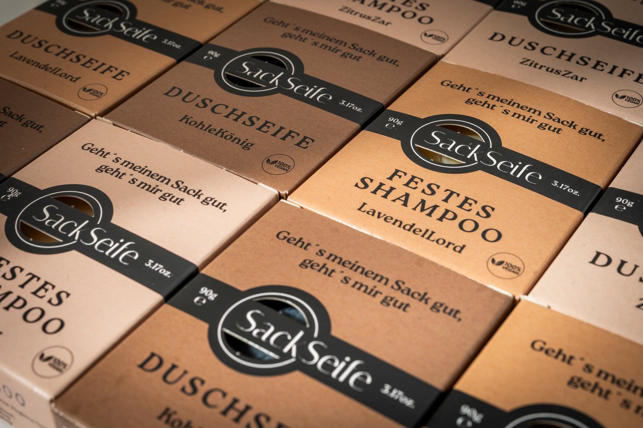 Mehrere Verpackungen mit "SackSeife" und verschiedenen Produktbezeichnungen. Braune Kartons mit Produktinformationen und Logo.