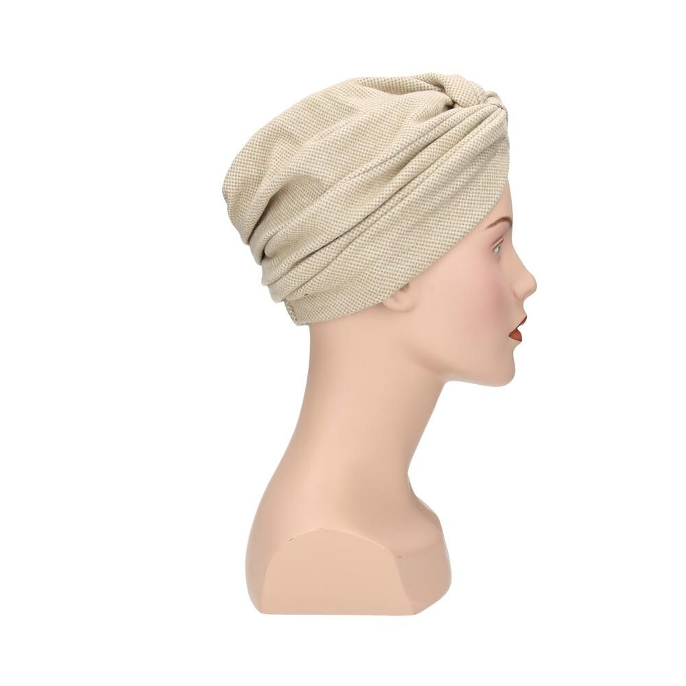 Beigefarbener Turban aus Stoff mit Knoten vorne, Seitenansicht auf einer Schaufensterpuppe.
