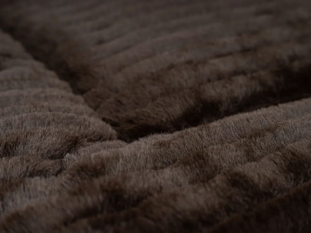 Braune, gefütterte Liegedecke mit geriffelter Oberfläche. Nahaufnahme, Textur sichtbar.