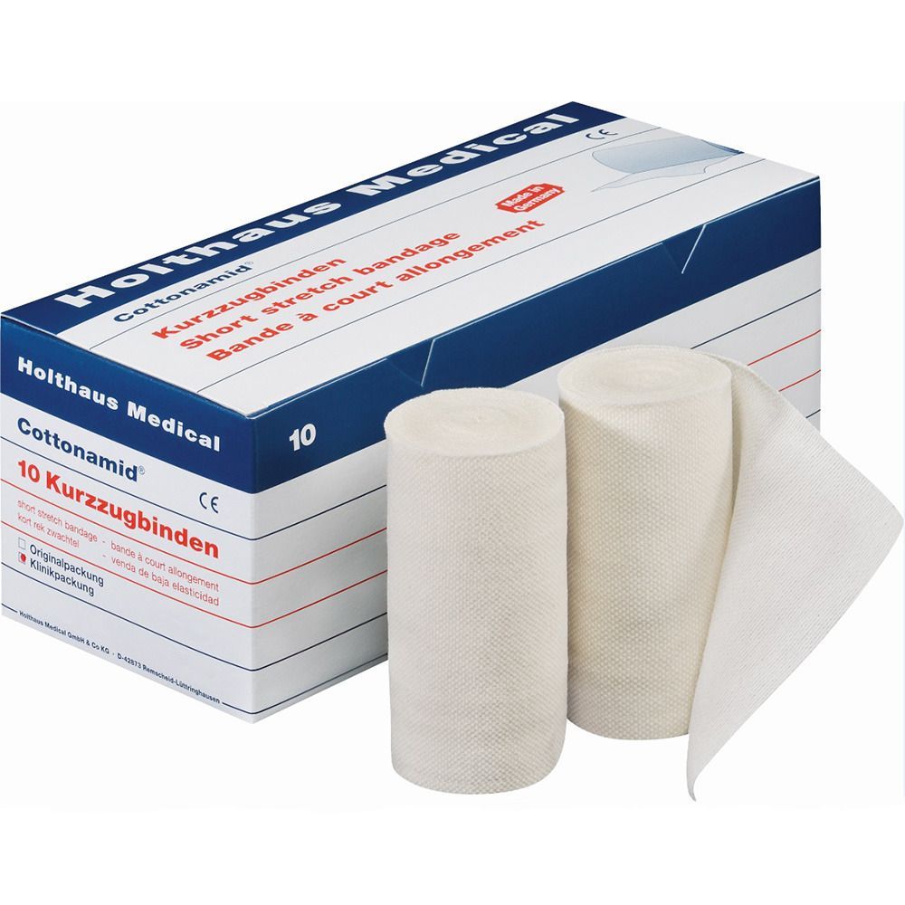Verpackung mit 10 Kurzzugbinden. Zwei Rollen und eine teilweise abgerollte Binde liegen daneben. Aufschrift: Cottonamid, Holthaus Medical.