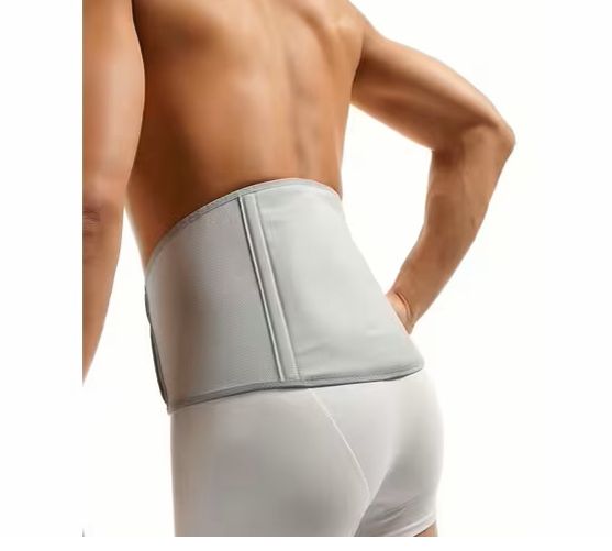Mann trägt eine graue OFA Push care Lumbalbandage. Die Bandage bedeckt den unteren Rücken. Graue Klettverschlüsse.