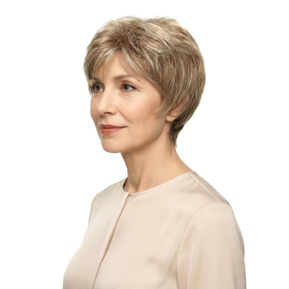 Kurzhaarperücke in Blondtönen. Seitliche Ansicht einer Frau mit Perücke. Helles Oberteil, weißer Hintergrund.