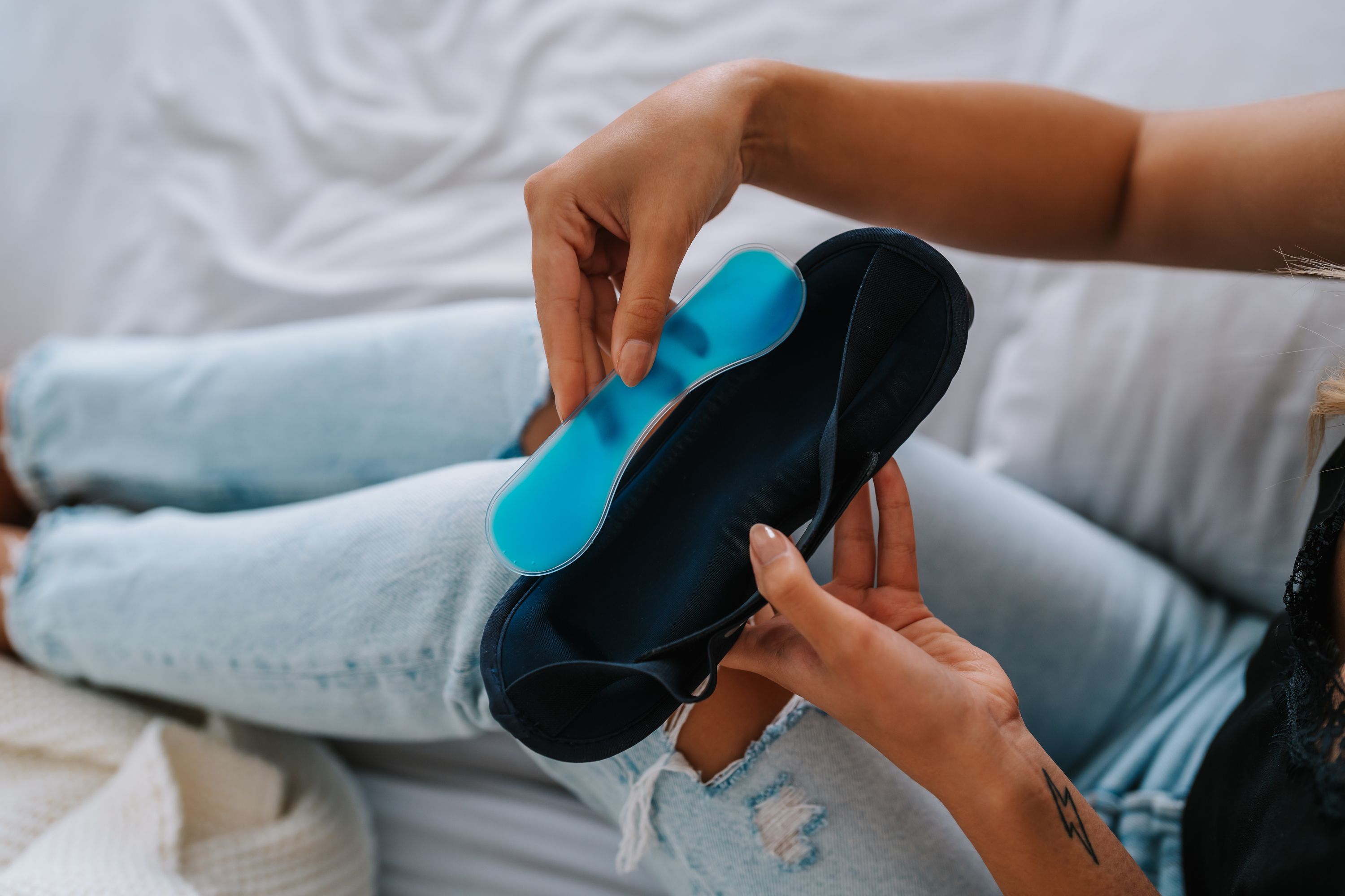 Hände halten blaues Kühlgel und blaues Augenmassagegerät. Nahaufnahme, Fokus auf die Hände.