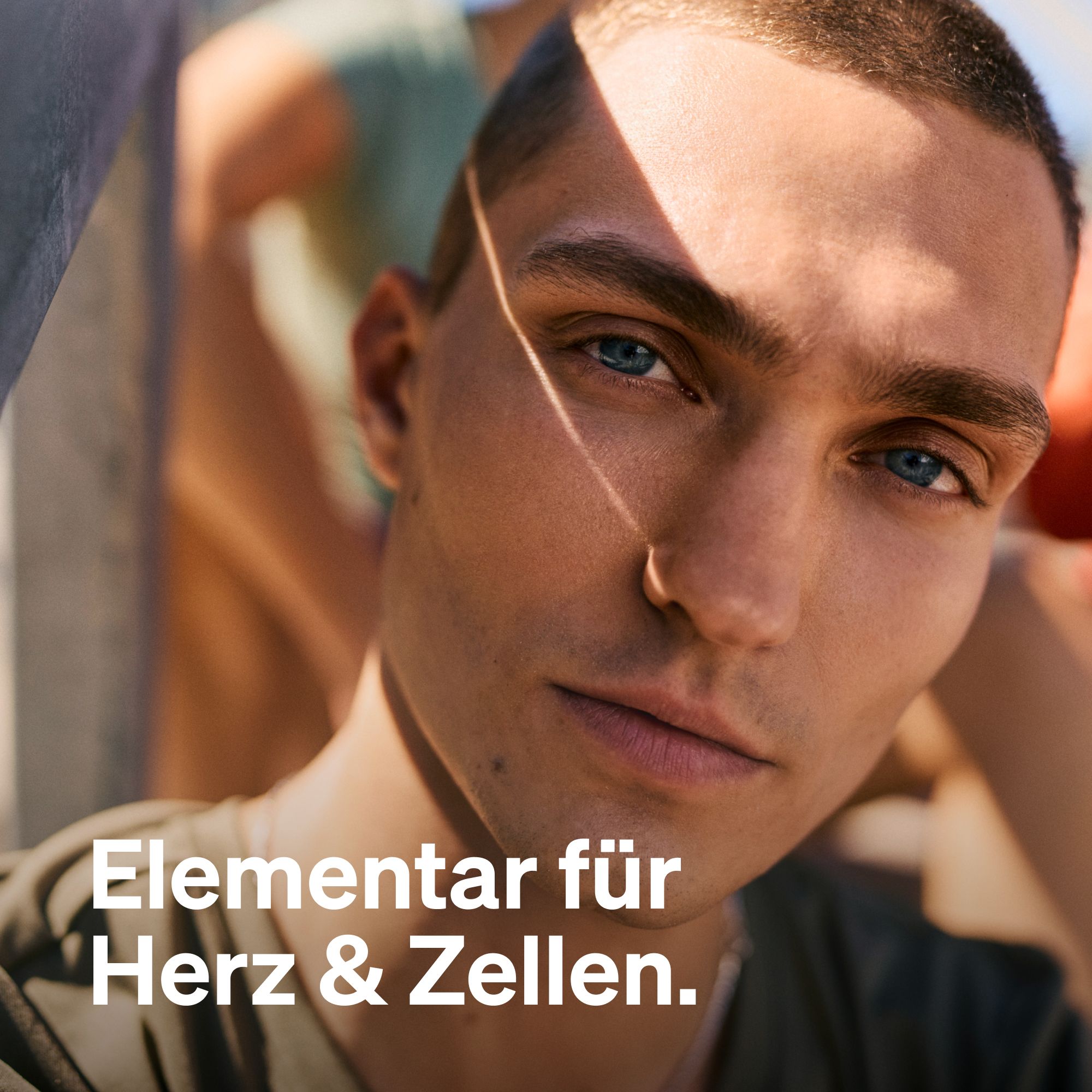 Porträt eines jungen Mannes mit blauem Augen. Text: Elementar für Herz & Zellen.