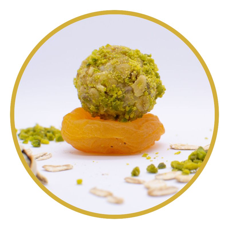 Kugel mit Pistazien auf einer Aprikose. Einzelne Pistazien und Haferflocken verstreut. Goldener Kreis.