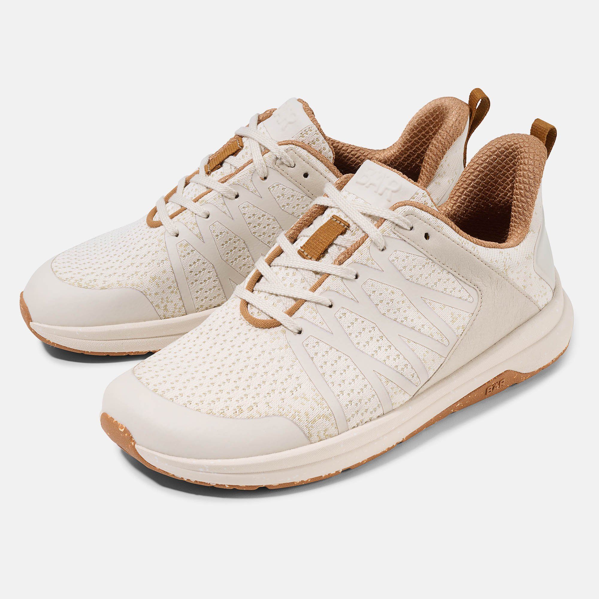 Zwei cremefarbene Unisex-Sneakers mit Schnürsenkeln. Braune Akzente an Zunge, Ferse und Sohle. Mesh-Obermaterial.