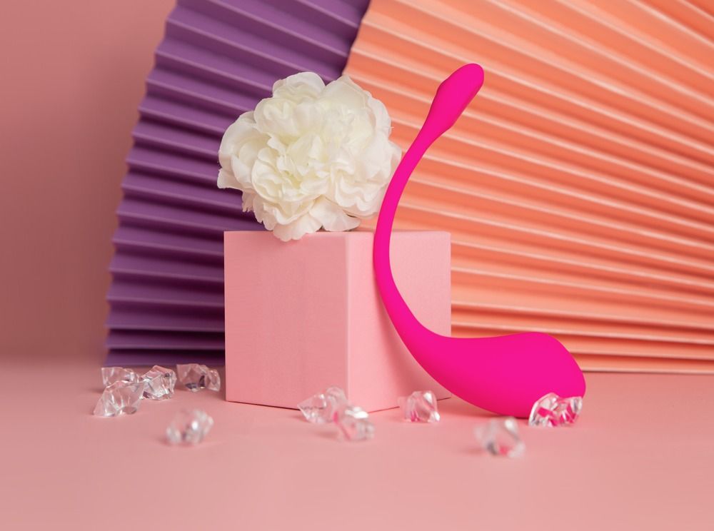 Rosa Ei-Vibrator auf einem rosa Podest, umgeben von Dekorationen.