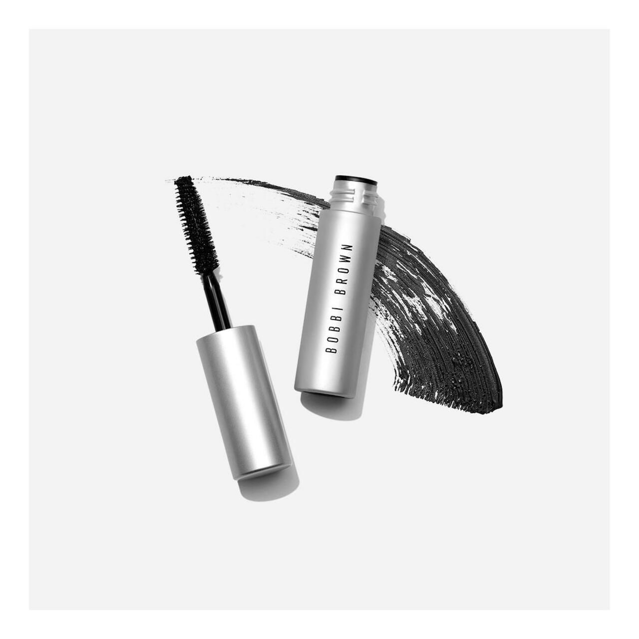Geöffnete Mascarahülse und Bürste neben einem schwarzen Mascara-Strich.