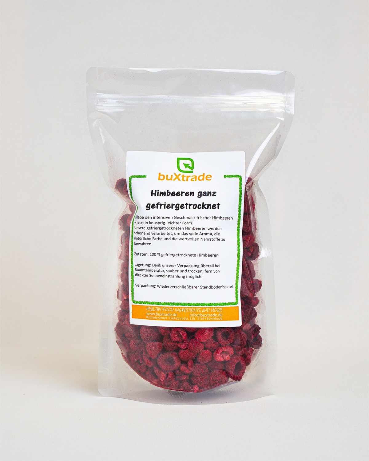 Transparente Verpackung mit gefriergetrockneten Himbeeren. Ein Etikett zeigt Produktinformationen und den Markennamen buXtrade.