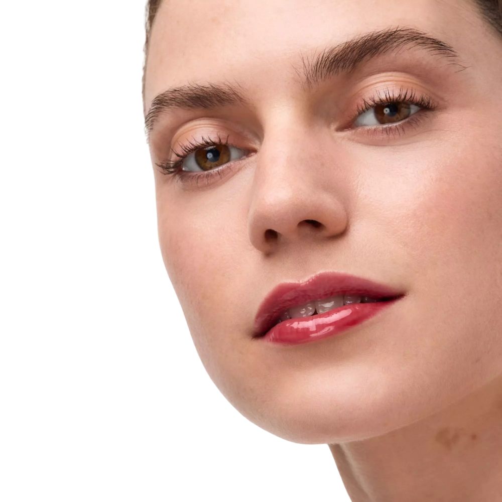 Nahaufnahme eines Gesichts mit glänzenden, roten Lippen und braunen Augen.