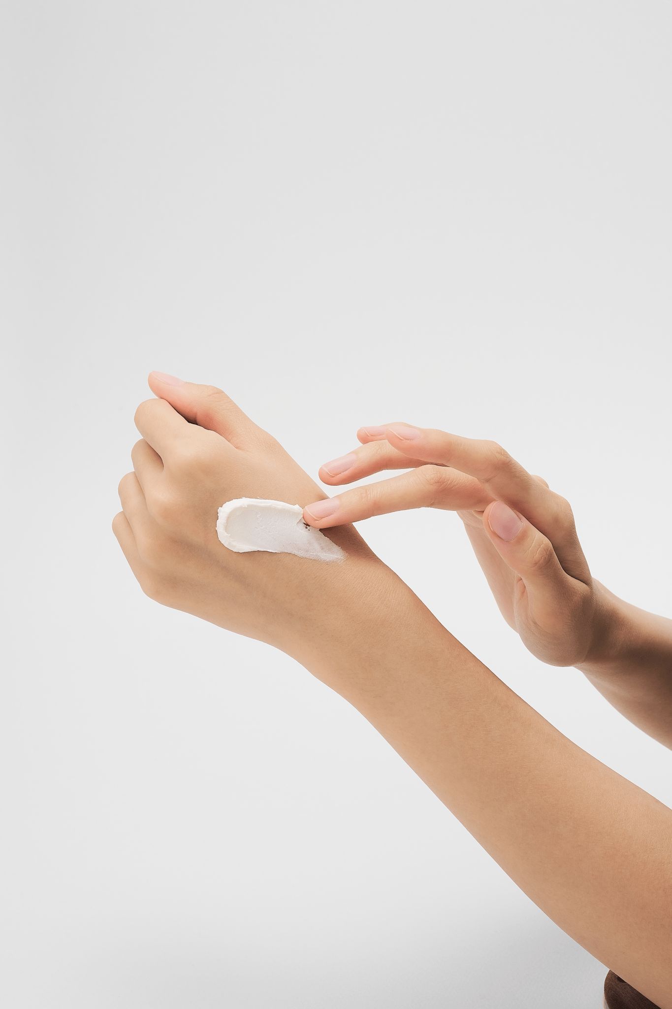 Eine Hand mit einer weißen Creme-Spur auf dem Handrücken, die von Fingern verrieben wird.