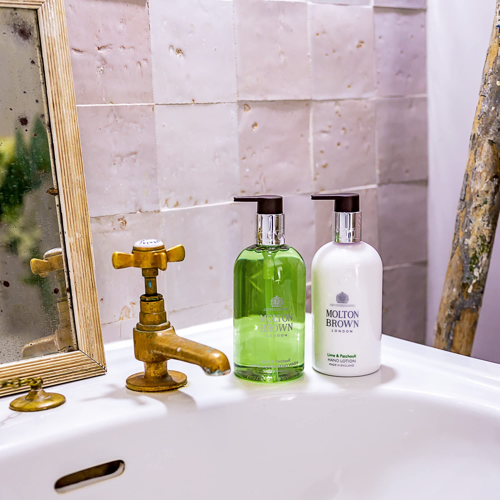 Zwei Seifenspender auf Waschbecken. Links: Grün. Rechts: Weiß. Molton Brown. Goldener Wasserhahn.