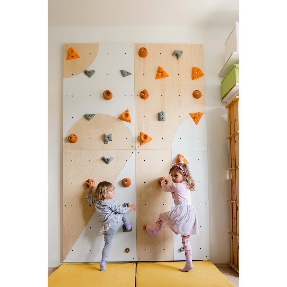 Kletterwand mit bunten Griffen. Zwei Kinder klettern an der Wand. Gelbe Matte am Boden.
