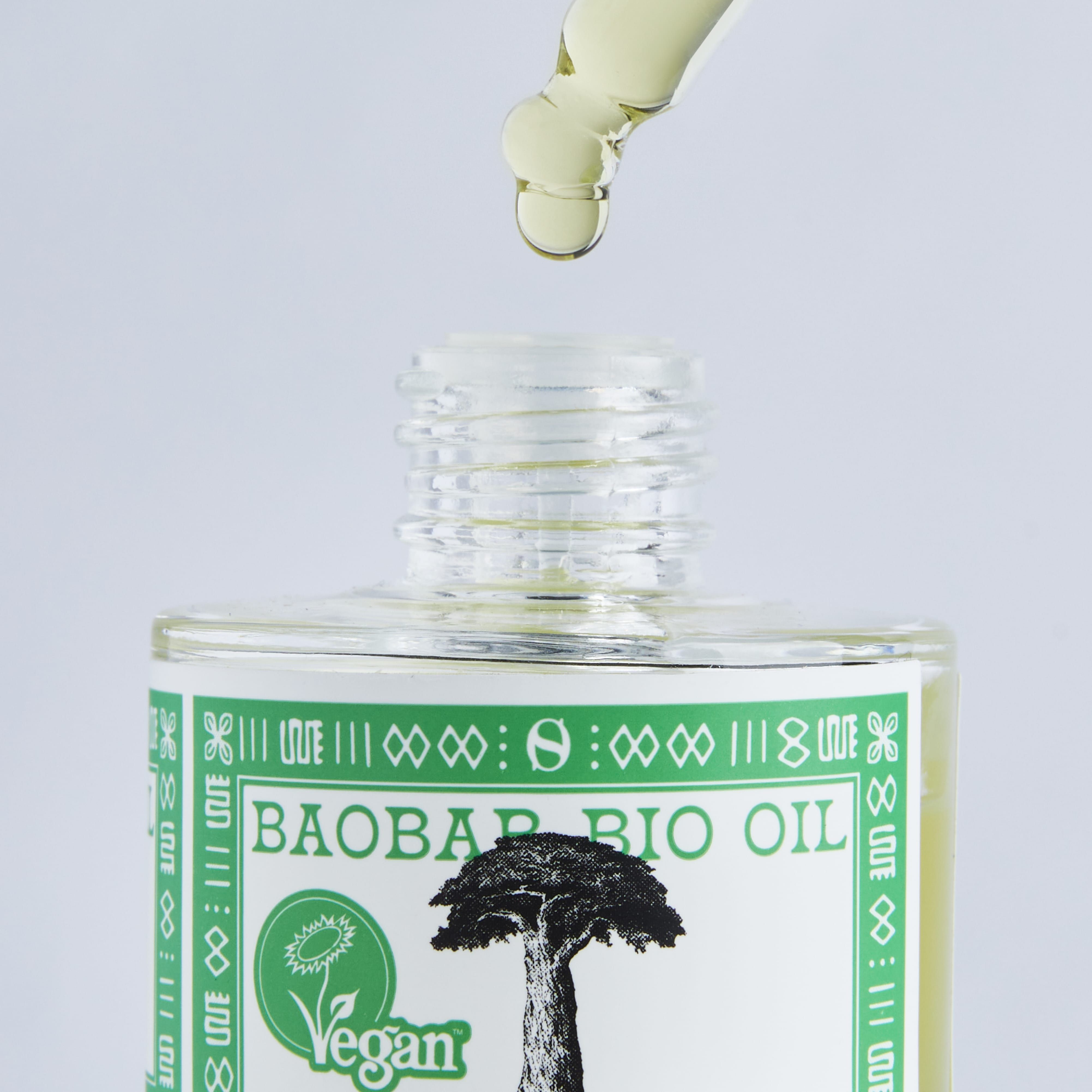 Flacone di olio di baobab. Gocce da pipetta. Sigillo vegano. Stampa verde con illustrazione di un albero.