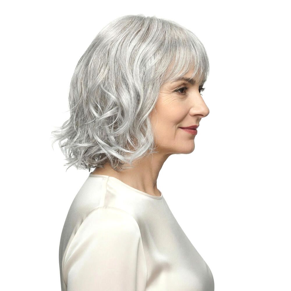 Perücke Capri, graues Haar mit Pony, wellig. Frau im Profil, helles Oberteil.