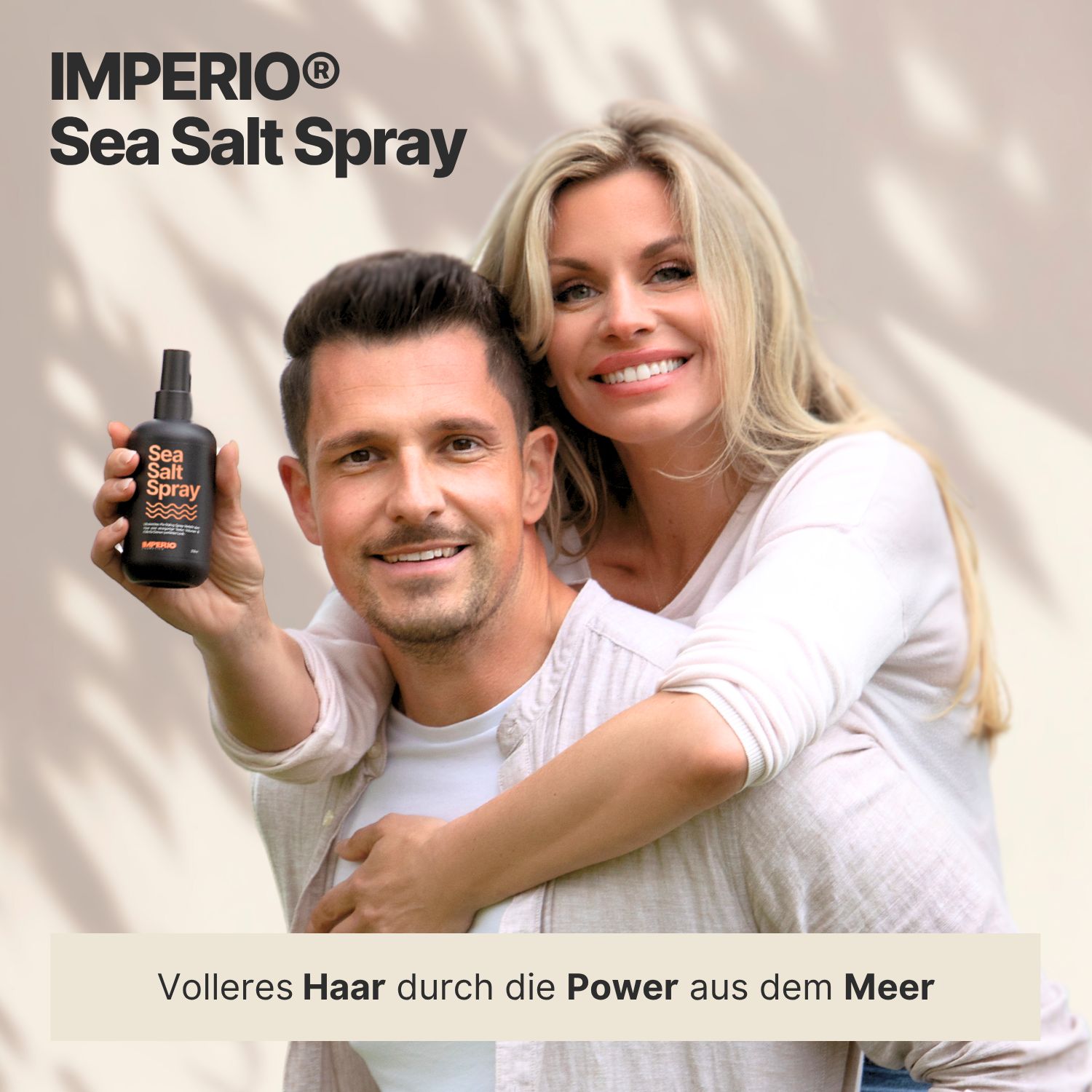 Mann und Frau umarmen sich. Frau hält Sea Salt Spray-Flasche. Hintergrund: hellbraun. Text: Volleres Haar durch die Power aus dem Meer.