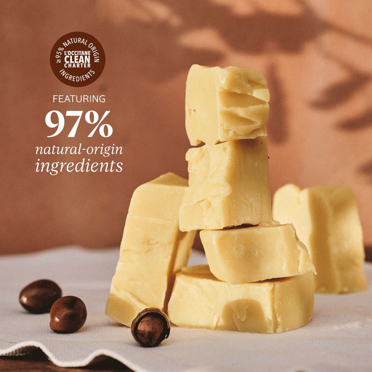 Stapel von Butterstücken und Sheanüssen. Text: 97% Inhaltsstoffe natürlichen Ursprungs. 95% natürliche Inhaltsstoffe.