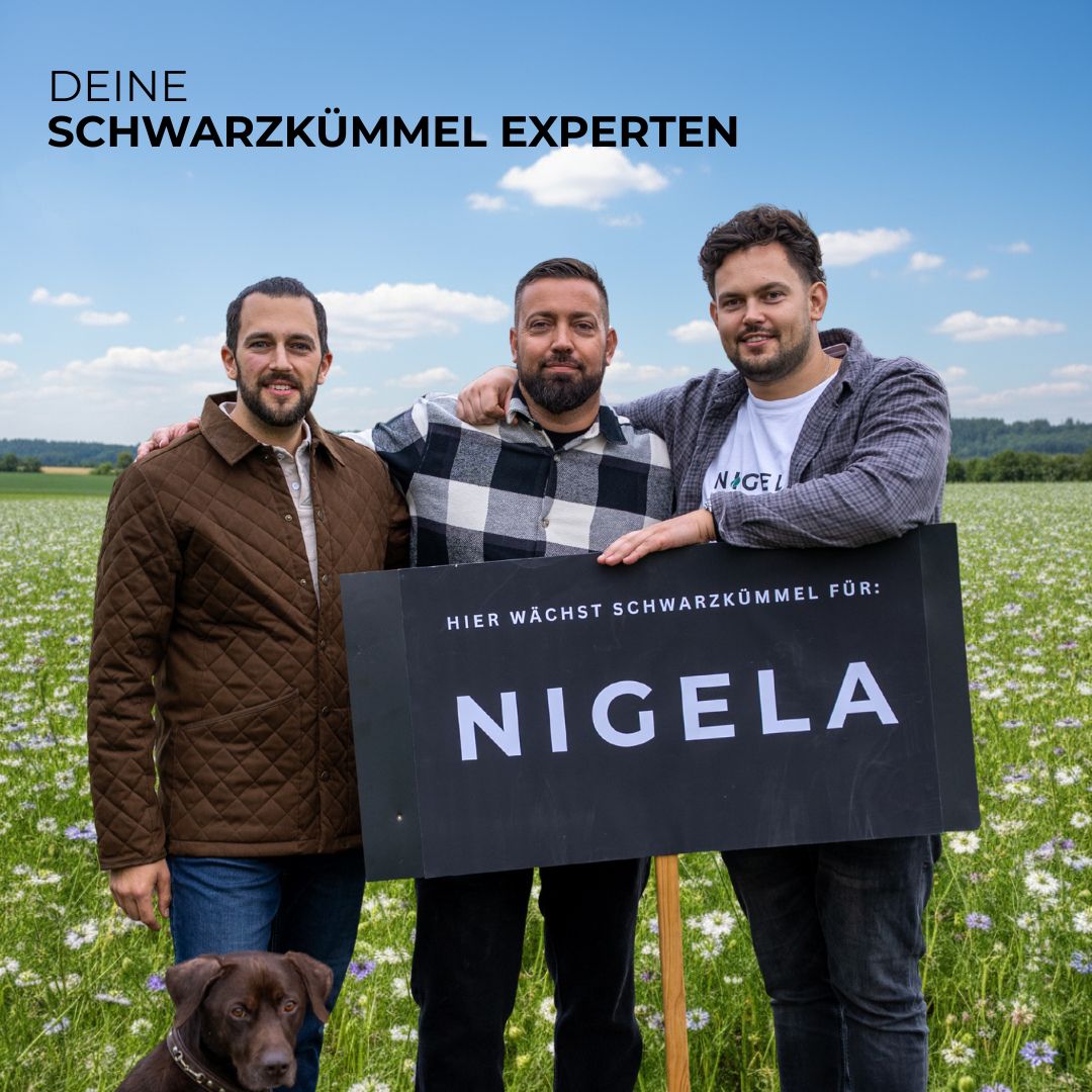 Drei Männer mit Schild: Hier wächst Schwarzkümmel für Nigela. Ein Hund im Feld.