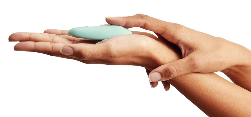 Türkisfarbener Vibrator in einer Hand gehalten. Hautfarbene Hände. Weißer Hintergrund.