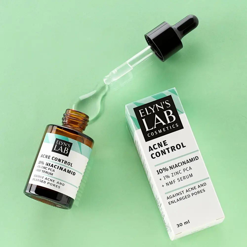 Braune Glasflasche mit Pipette und Tropfen. Daneben eine Schachtel. Aufschrift: ELYN'S LAB, Acne Control, 10% Niacinamid, 1% Zink PCA, NMF Serum. Gegen Akne und vergrößerte Poren.