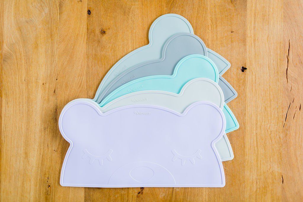 Mehrere Platzdeckchen in Bärenform, in verschiedenen Farben. Auf Holzuntergrund.