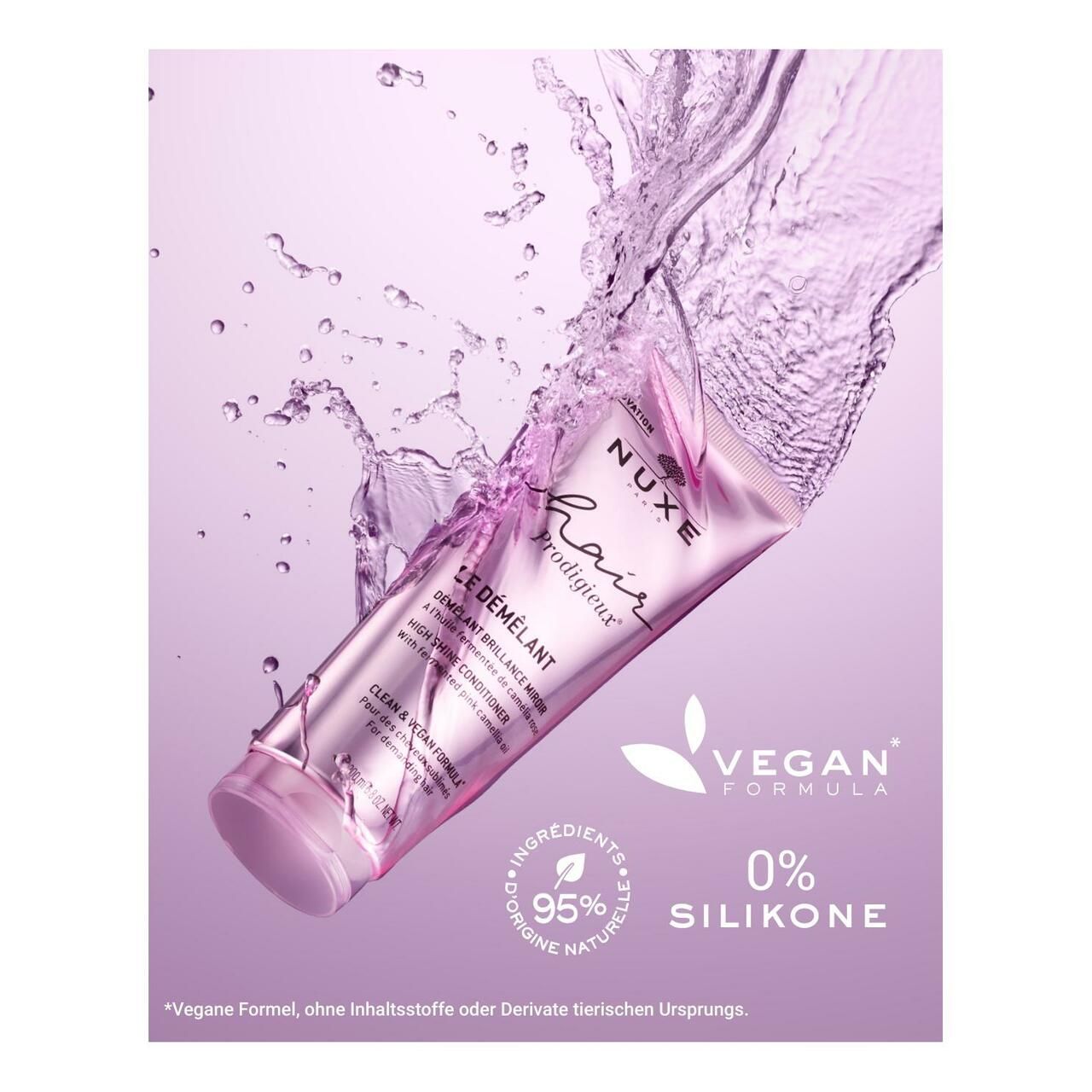 Rosa Tube NUXE Hair Prodigieux Glanz-Conditioner, umgeben von Wasser. Text auf der Tube.